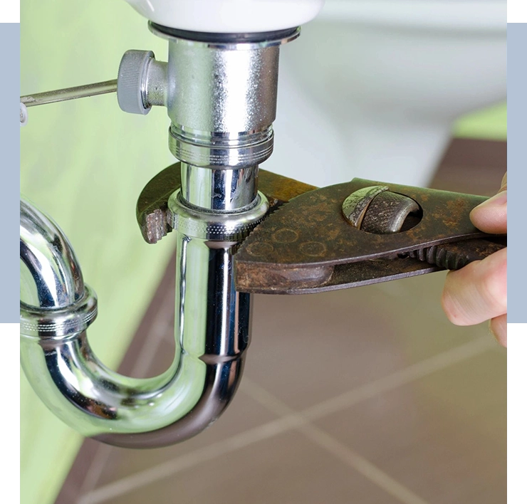A person is holding a wrench and fixing the faucet.