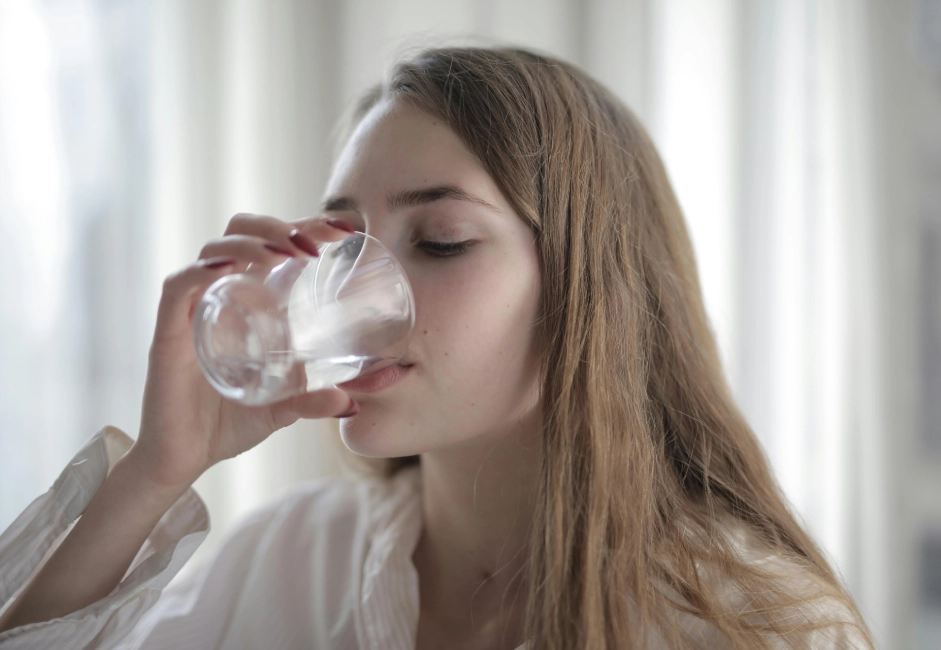 A woman drinking water from a glass.