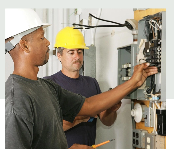 Two men in hard hats working on a circuit board.